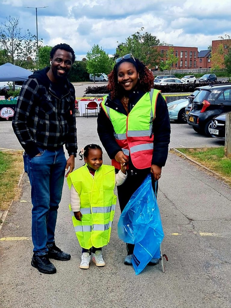Family volunteers cleaning up with litter pickers and rubbish bags in hi visibility jackets at the community clean-up