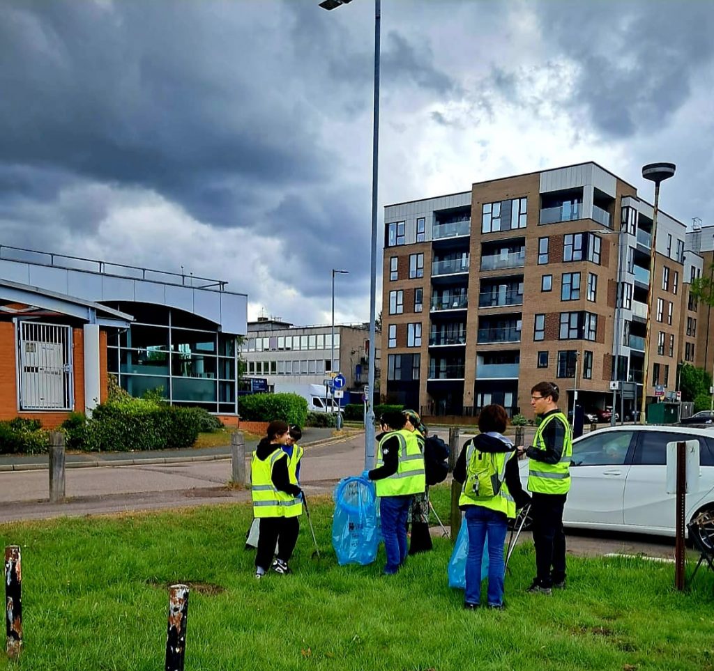Team of volunteers cleaning up with litter pickers and rubbish bags in hi visibility jackets