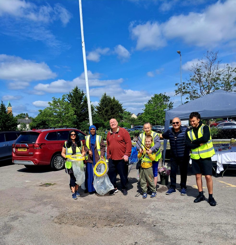 Team of volunteers cleaning up with litter pickers and rubbish bags in hi visibility jackets at the community clean-up