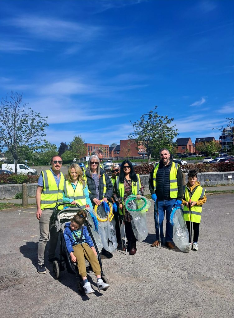 Team of volunteers cleaning up with litter pickers and rubbish bags in hi visibility jackets at the community clean-up